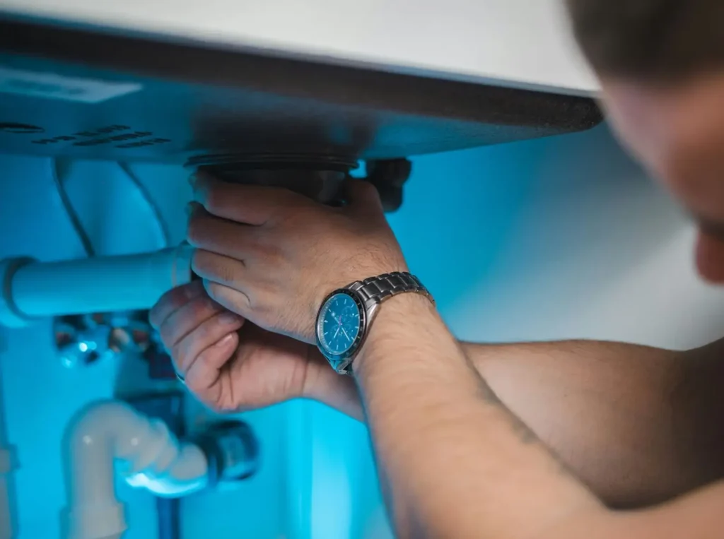 Person fixing plumbing under sink